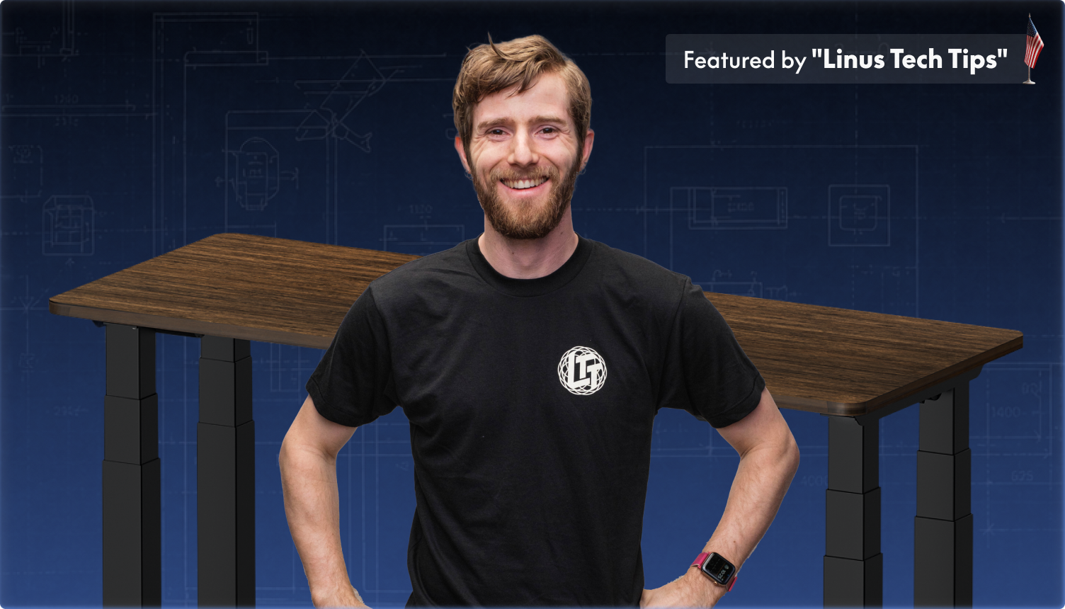 Adjustable standing desk with a dark wood tabletop and black frame, featured by Linus Tech Tips, highlighting ergonomic design and digital controls.